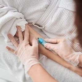 Close up of medical worker hands in sterile gloves doing injection with syringe in woman v