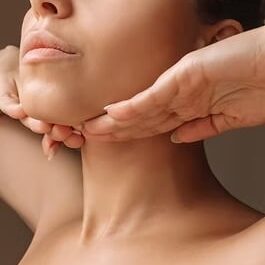 Cropped shot of young caucasian woman touching under the chin with hands massaging her fac